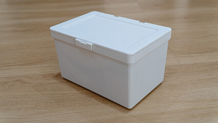Open white storage box. Placed on a wood textured floor.