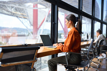 Focused financial specialist latin hispanic businesswoman working on laptop pc sitting at desk in modern office. Middle eastern or european woman using computer for finance data analysing work online