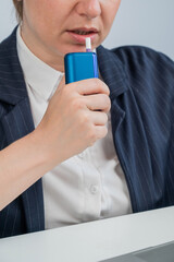 Business woman smoking an electronic cigarette while working on a laptop. Tobacco heating system.