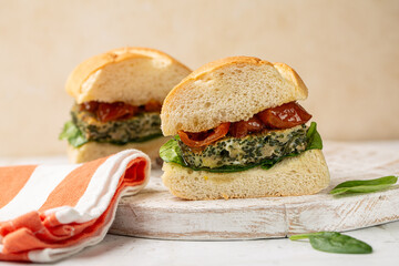 Sandwich with pan-fried omelette or egg frittata with agretti or so colled monk's beard, sun dried tomatoes, spinach, soft bread. Spring  food, seasonal herb, popular ingredient in Italian cuisine.