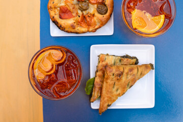 Top view of glass with Aperol Spritz,  pre-dinner drinks, and complimentary italian snacks. ...