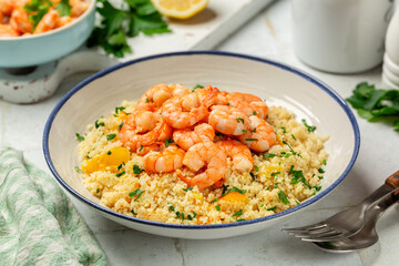 Summer lunch with Couscous and fried Shrimps, yellow tomatoes, onion, parsley.  Close up. White table surface.