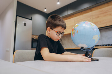 Curious boy learning geography rotating a globe at home