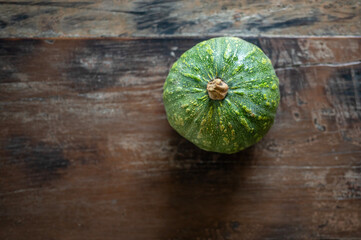 Green pumpkin resting on a wooden table