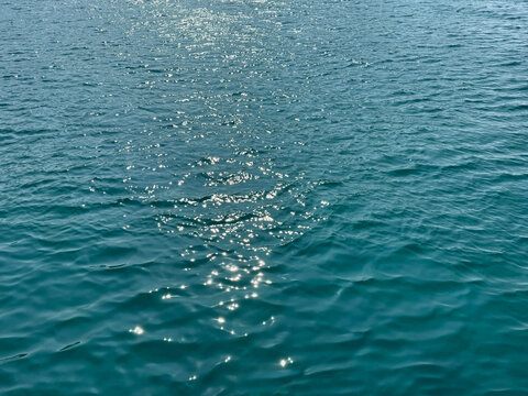 Blue sea waves with sun reflections on surface .