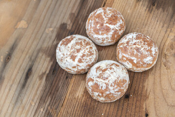 Four small round balls of gingerbread cookies, covered in sugar, on a wooden table. Close-up, food photography,