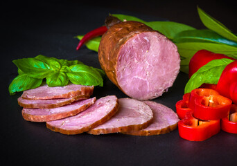 Sausage, ham with peppers and herbs on a dark background
