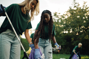 Volunteers picking up trash in park wearing matching shirts