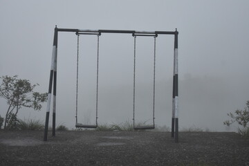 Empty swing set shrouded in thick fog, evoking a sense of mystery.