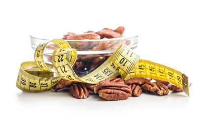 Peeled pecan nuts and measuring tape isolated on white background.