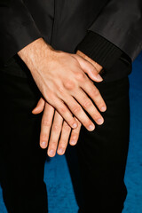 Obraz premium Closeup of crossed hands against a dark backdrop, capturing a moment of pause or quiet contemplation in a monochromatic color scheme.