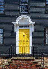 Bright yellow door and a porch in the traditional old New England home in Rhode Island
