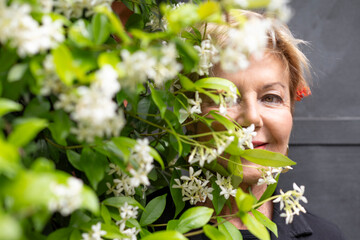 the subtle portrait of a woman partially obscured by the lush white blossoms of a vibrant flowering...