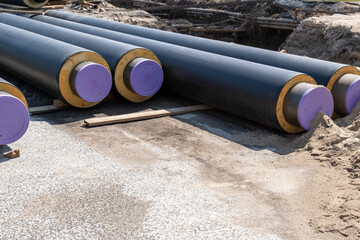 insulated pipes  as utility installations for water, gas, or district heating system. tube with black surfaces and yellow ends are laid out on a construction site. materials  infrastructure projects