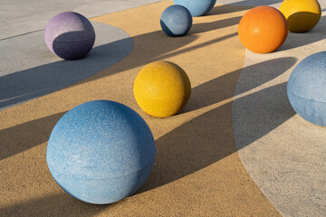 Concrete spheres Colorful objects of different sizes rest on a textured surface with shadow...