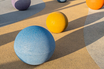 Concrete spheres Colorful objects of different sizes rest on a textured surface with shadow...
