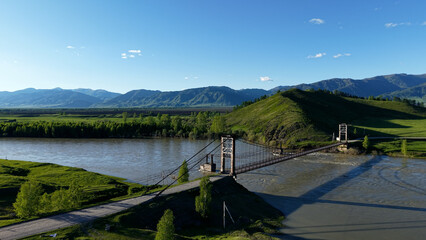 Fototapeta premium A bridge in the village of Multa in the Altai Mountains. A bridge across a cold mountain river in the mountains of the Altai Republic.