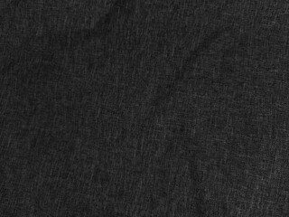 Dark textured fabric with visible weave pattern, creating an uneven surface. The appearance is matte and slightly wrinkled, suggesting soft material with a subtle shadow effect