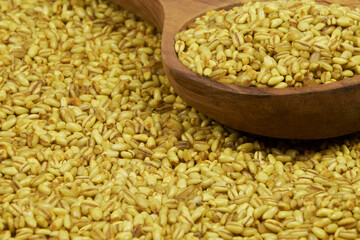 Whole wheat isolated on a rustic background. Wheat grains with ceramic and wooden containers, close-up photo.
