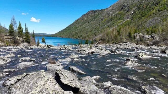 Cinematic views of a mountain lake with high mountains. Multinsky lakes are high-mountain lakes in the Altai Mountains. Rapids of water between two lakes, drone flight over running water.