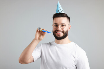Happy Birthday. Handsome man with party hat and blower on grey background