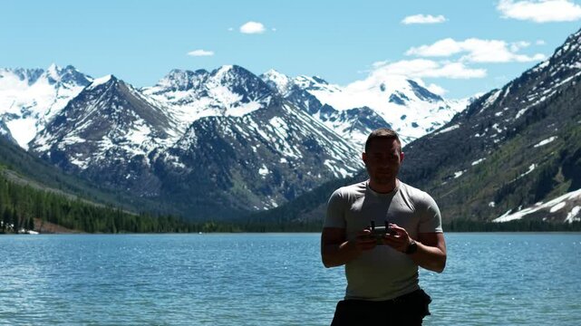 Cinematic views of a mountain lake with high mountains. Multinsky lakes are high-mountain lakes in the Altai Mountains. A man takes a selfie during a trip to the Altai Mountains.