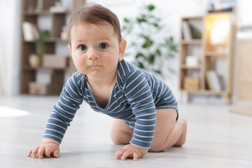 Cute little baby crawling on floor at home