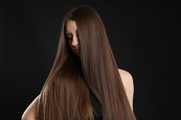 Beautiful teenage girl with healthy long hair on black background