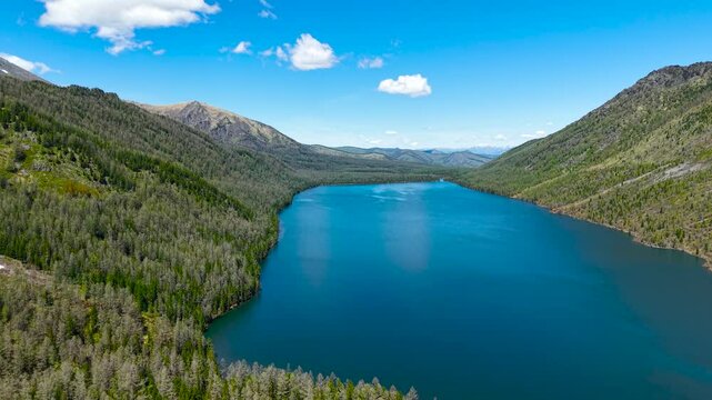 Cinematic views of a mountain lake with high mountains. Multinsky lakes are high-mountain lakes in the Altai Mountains. View from a great height of a lake surrounded by mountains 4k