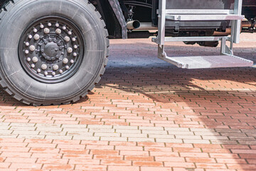 Close-up view of a wheel with thick tread, attached to a hub with bolts Background suggests brick...