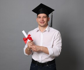 Happy student with diploma after graduation on grey background
