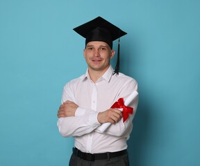 Happy student with diploma after graduation on light blue background