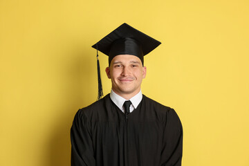 Portrait of student after graduation on yellow background