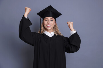 Happy student after graduation on grey background