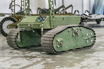 Image of a green all-terrain, rugged Ukrainian military mini robot UGV with caterpillar tracks, indoor concrete setting, potential military or industrial use, robust construction, neutral perspecti