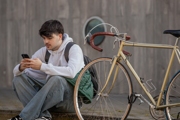 urban scene of young man with mobile phone and vintage bicycle