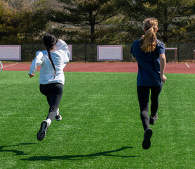 Two female athletes bounding on a turf field for strength and speed
