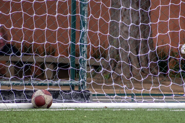 old leather soccer ball on the grass inside the goal in a soccer field in Brazil