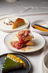 A selection of decadent desserts showcases vibrant colors and unique textures. Flaky pastries are topped with sweet sauces and crunchy toppings, inviting enjoyment in an intimate setting