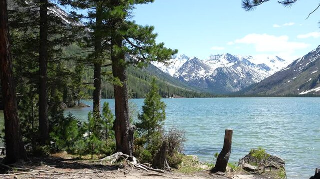Beautiful lakes in the mountains. Multinsky lakes in the Altai mountains. Mountains with snowy peaks in the distance in the background, a mountain lake in the foreground