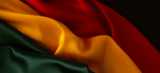 Naklejka na ściany i meble Black History Month, Juneteenth background. Red, yellow, green colors satin silk flag draperies. Top view