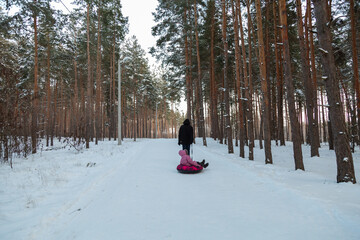 Dad with his daughter walking with snow tubing in the winter forest
