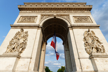 The Triumphal Arch decorated with National French flag, Paris, France. Inscription on arch in French: names of battles -proper nouns.