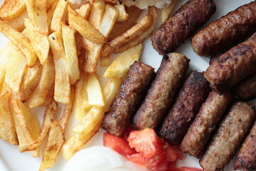 A balkan traditional meatball dish cevapi, cevapcici  on wooden table in close-up	