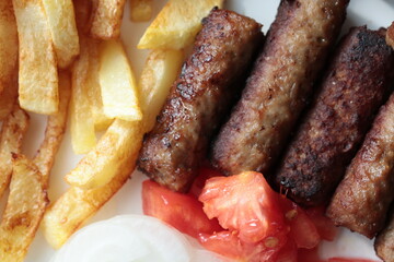 A balkan traditional meatball dish cevapi, cevapcici  on wooden table in close-up	