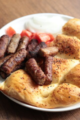 A balkan traditional meatball dish cevapi, cevapcici  on wooden table in close-up	