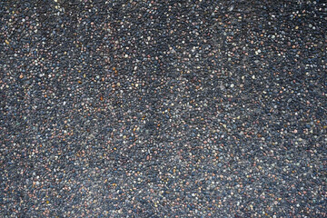 Close-up of colorful gravel texture on asphalt surface, top view.
