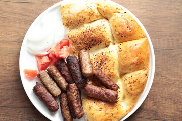 A balkan traditional meatball dish cevapi, cevapcici  on wooden table in close-up	