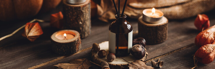Banner. Aroma reed diffuser, pumpkins, knitted sweaters, candles, dry leaves on wooden table. Concept of house decor, apartment seasonal fragrance. Thanksgiving. Autumn mood, cozy fall home atmosphere