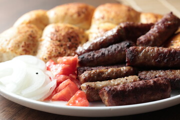 A balkan traditional meatball dish cevapi, cevapcici  on wooden table in close-up	